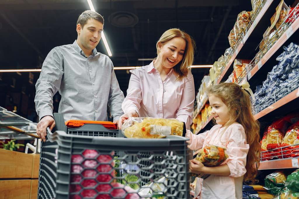 Casal com filha fazendo compra em supermercados com vale alimentação