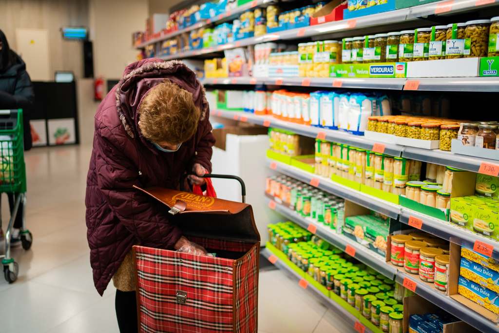 Senhora em supermercado, analisando a própria cesta de compras, simbolizando vale cesta básica e vale alimentação